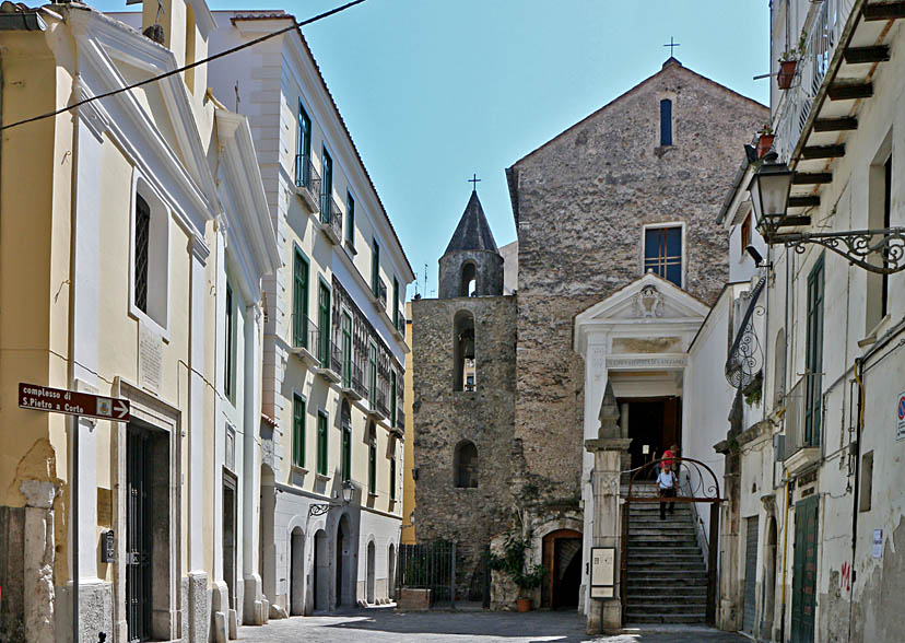 Largo San Pietro a Corte  (oggi)- L'ingresso all'Ipogeo (a sinistra delle scale), a destra del campanile e del Palazzo Fruscione. A sinistra , del largo (piazzetta), in primo piano Chiesa di S.Matteo Piczulo poi S.Stefano